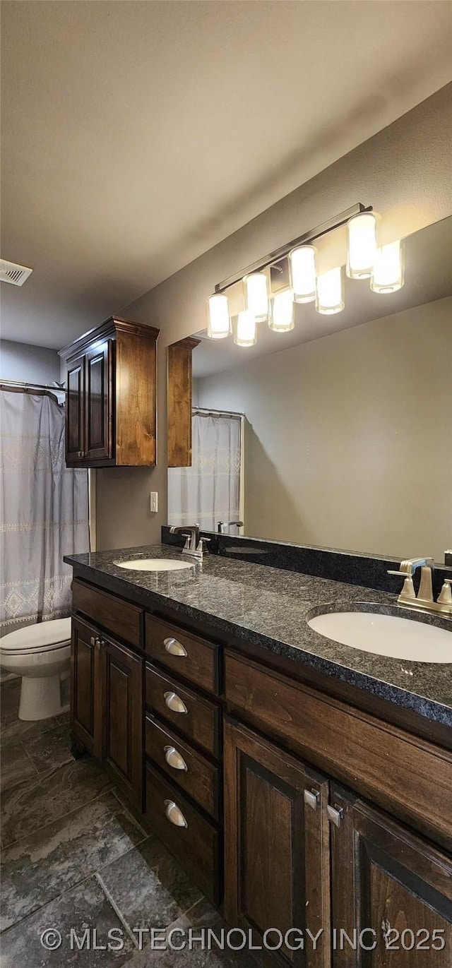 full bathroom featuring double vanity, visible vents, toilet, and a sink