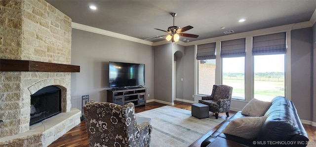 living room with visible vents, a ceiling fan, wood finished floors, crown molding, and a fireplace