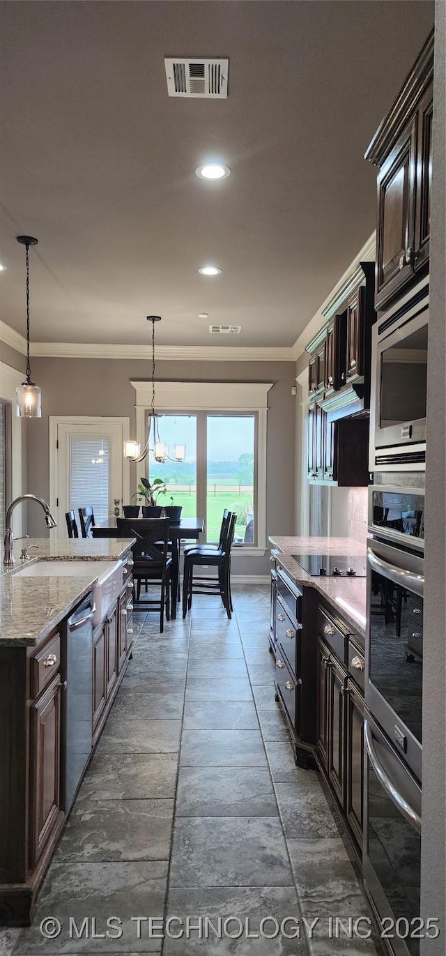 kitchen with stainless steel appliances, a sink, visible vents, light stone countertops, and hanging light fixtures
