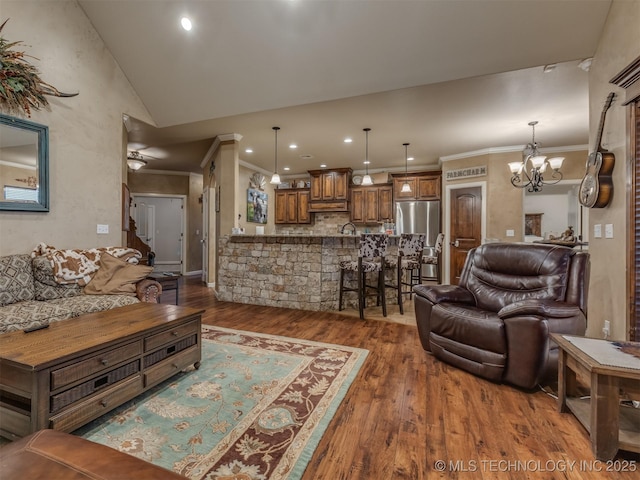 living room with vaulted ceiling, hardwood / wood-style flooring, an inviting chandelier, ornamental molding, and recessed lighting