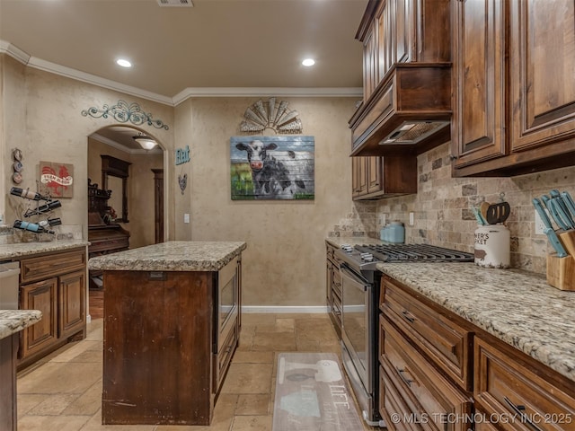 kitchen with stone tile flooring, arched walkways, ornamental molding, and stainless steel gas range oven