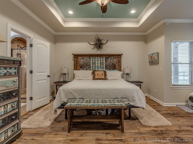 bedroom featuring a raised ceiling, wood finished floors, and ornamental molding