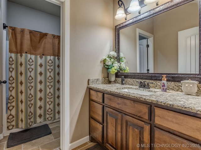 bathroom with baseboards, vanity, and a shower