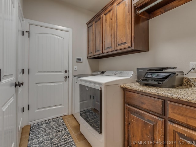 laundry room with separate washer and dryer, light tile patterned floors, and cabinet space