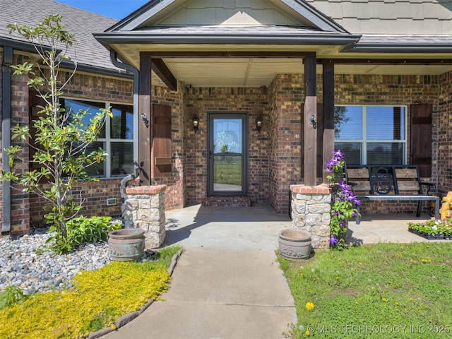 doorway to property featuring brick siding, a porch, and board and batten siding