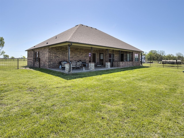 rear view of property with fence, a patio area, brick siding, and a yard