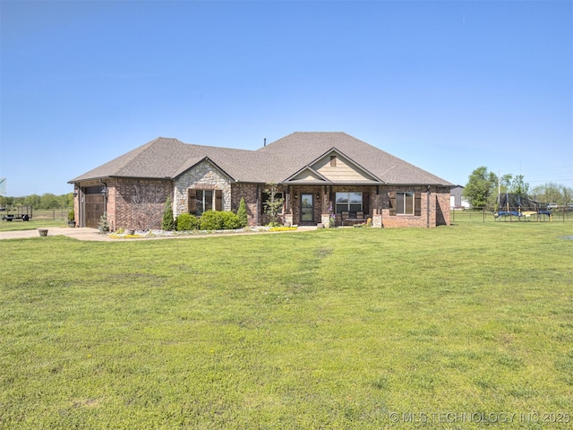 ranch-style home with brick siding, a trampoline, roof with shingles, and a front lawn