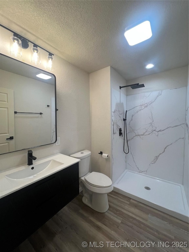 4232 N Hartford Ave, Tulsa, OK 74106 - bathroom with a textured ceiling, vanity, toilet, wood finished floors, and a marble finish shower
