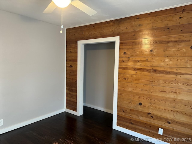 218 SW B, Ardmore, OK 73401 - spare room featuring baseboards, wood walls, ceiling fan, and dark wood finished floors