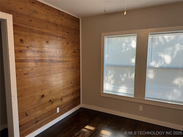 218 SW B, Ardmore, OK 73401 - unfurnished room with dark wood-type flooring, wooden walls, baseboards, and healthy amount of natural light