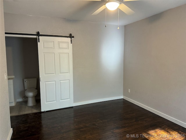218 SW B, Ardmore, OK 73401 - unfurnished bedroom with a barn door, dark wood-type flooring, baseboards, and a ceiling fan