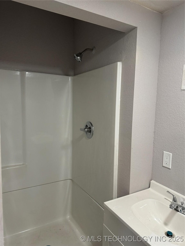 218 SW B, Ardmore, OK 73401 - bathroom featuring a textured wall, a shower, and a sink