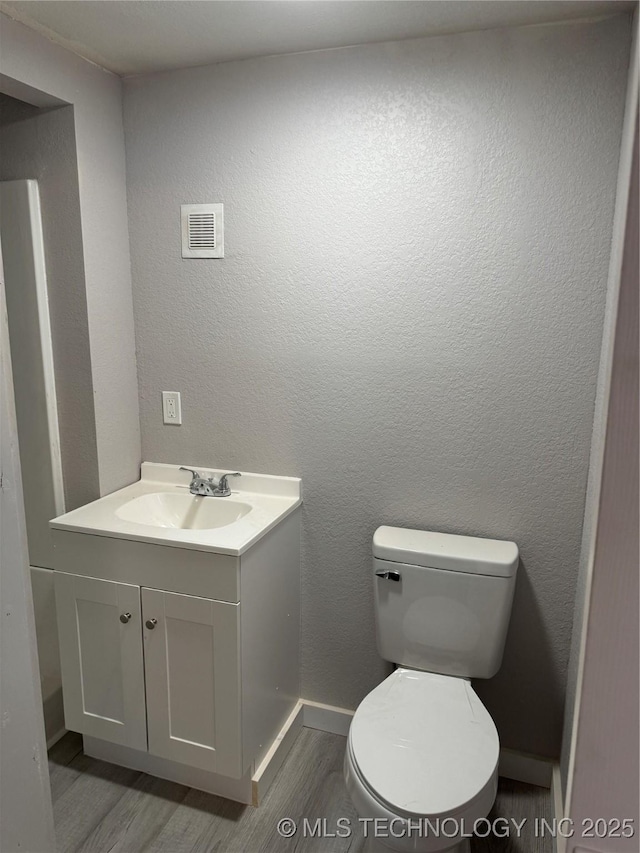 218 SW B, Ardmore, OK 73401 - bathroom featuring wood finished floors, toilet, vanity, and baseboards