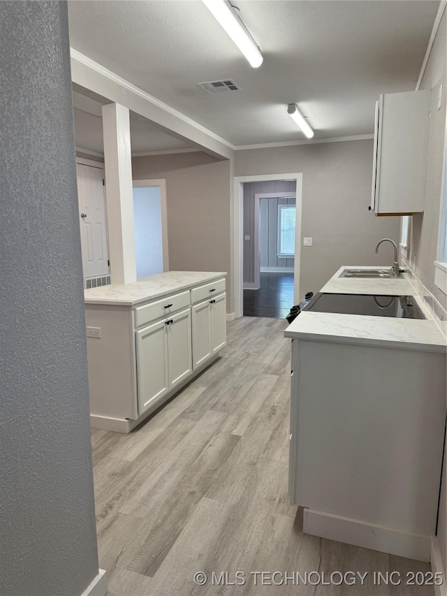 218 SW B, Ardmore, OK 73401 - kitchen with a sink, light wood finished floors, crown molding, white cabinets, and baseboards
