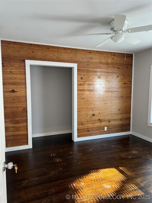 218 SW B, Ardmore, OK 73401 - unfurnished room featuring wood walls, ceiling fan, baseboards, and dark wood-type flooring