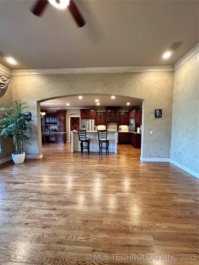 10213 S 88th E Ave, Tulsa, OK 74133 - unfurnished living room with arched walkways, a ceiling fan, wood finished floors, ornamental molding, and recessed lighting