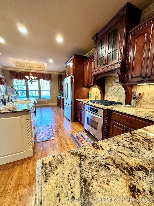 10213 S 88th E Ave, Tulsa, OK 74133 - kitchen featuring stainless steel appliances, crown molding, light wood finished floors, light stone countertops, and backsplash