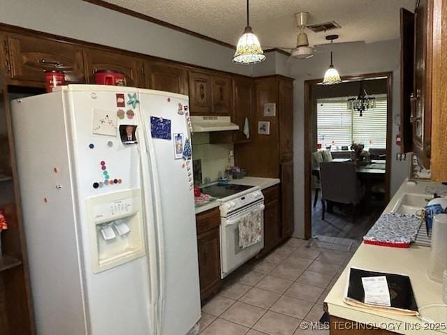 901 S Anthony St, Muskogee, OK 74403 - kitchen featuring white appliances, under cabinet range hood, light countertops, light tile patterned floors, and decorative light fixtures