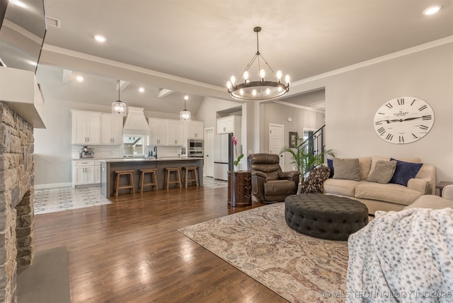 living room with dark wood-style flooring, ornamental molding, and a notable chandelier