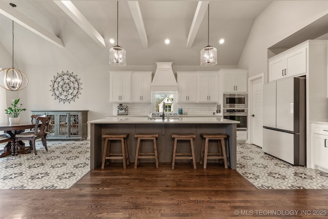 kitchen with decorative backsplash, white cabinets, appliances with stainless steel finishes, a breakfast bar, and an island with sink