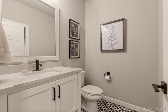 bathroom with baseboards, toilet, and vanity