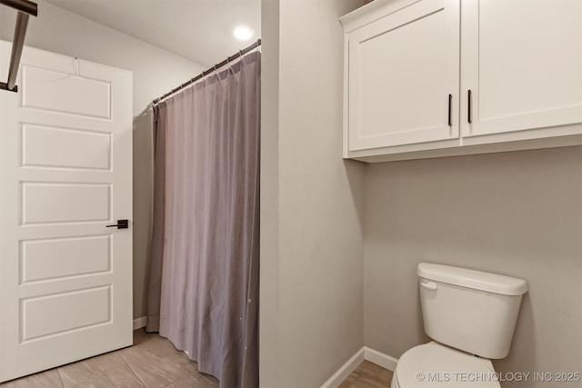 bathroom featuring baseboards, toilet, and a shower with curtain