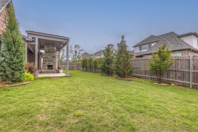 view of yard with a patio, an outdoor stone fireplace, and a fenced backyard