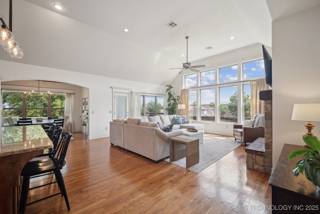 living area featuring arched walkways, wood finished floors, a ceiling fan, and visible vents