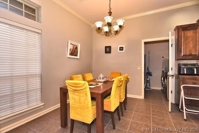 dining space featuring dark tile patterned flooring, a notable chandelier, ornamental molding, and baseboards