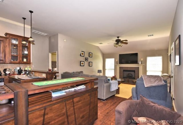living room featuring a tile fireplace, visible vents, a ceiling fan, and dark wood-style floors