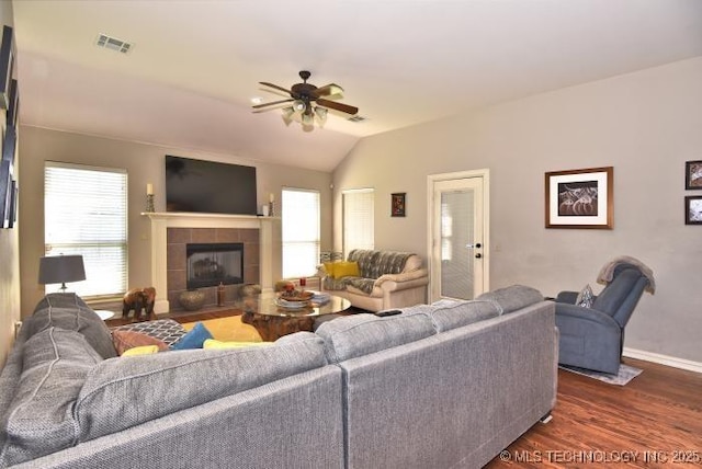 living room featuring visible vents, baseboards, a ceiling fan, dark wood finished floors, and a tile fireplace