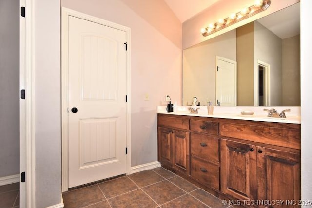 bathroom featuring tile patterned floors, a sink, double vanity, and lofted ceiling