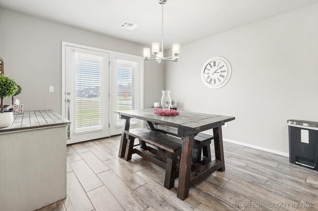 dining area featuring a notable chandelier, light wood finished floors, and visible vents