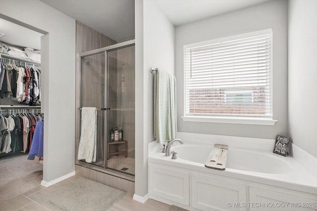 full bathroom featuring a spacious closet, a garden tub, and a stall shower