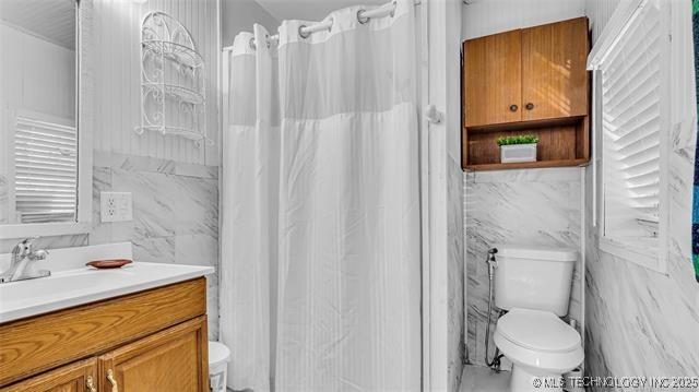 13760 SW Wilderness, Kingston, OK 73439 - full bath featuring toilet, vanity, a shower with shower curtain, and tile walls