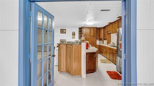 13760 SW Wilderness, Kingston, OK 73439 - kitchen featuring a center island, light countertops, light tile patterned flooring, visible vents, and brown cabinets