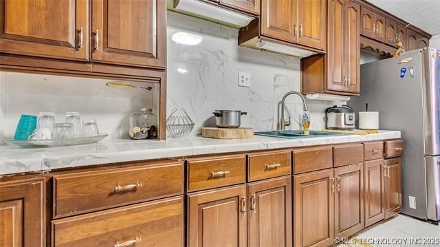 13760 SW Wilderness, Kingston, OK 73439 - kitchen featuring a sink, brown cabinets, decorative backsplash, and light countertops