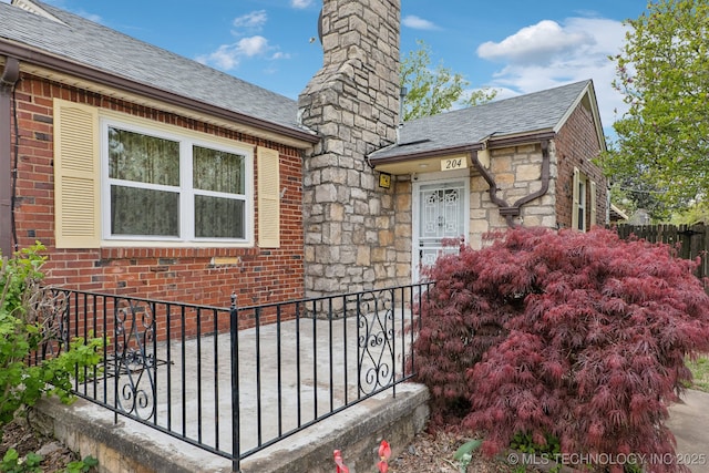 204 S Jamestown Ave, Tulsa, OK 74112 - entrance to property featuring roof with shingles, a chimney, stone siding, and brick siding