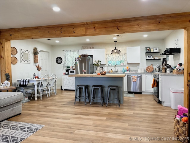kitchen featuring a center island, appliances with stainless steel finishes, beam ceiling, and a kitchen breakfast bar