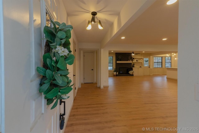 entryway with recessed lighting, light wood finished floors, a notable chandelier, and a large fireplace
