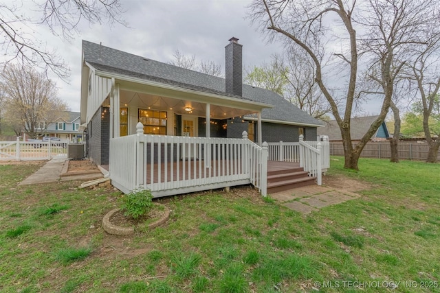 back of house featuring a yard, a chimney, a fenced backyard, a wooden deck, and roof with shingles