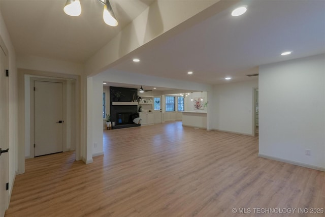 unfurnished living room featuring light wood-style floors, baseboards, and a glass covered fireplace