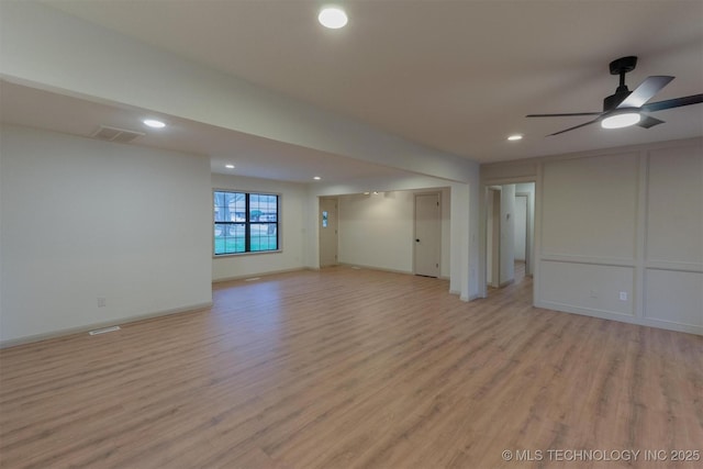 unfurnished living room featuring a decorative wall, light wood-style flooring, visible vents, and a ceiling fan