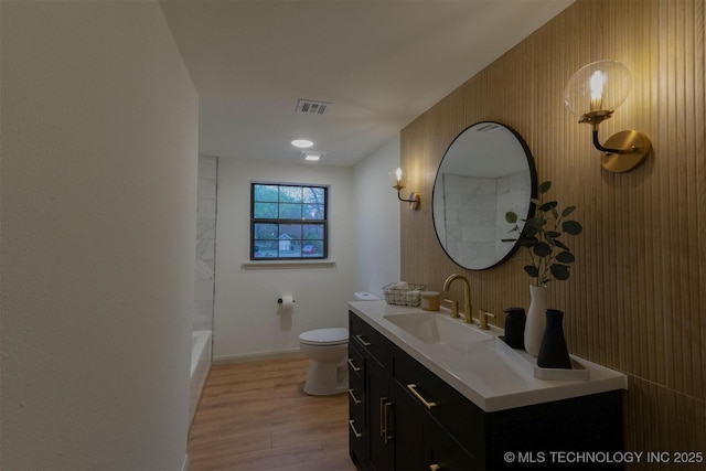 full bath featuring vanity, visible vents, toilet, wood finished floors, and baseboards
