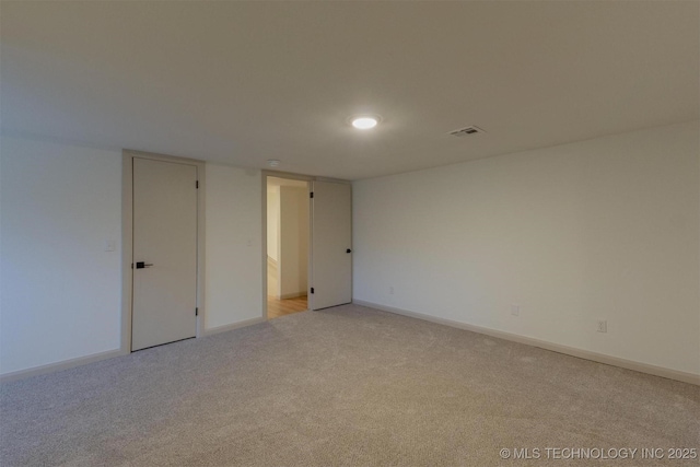 unfurnished room featuring visible vents, light colored carpet, and baseboards