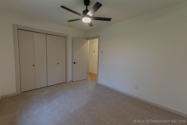 unfurnished bedroom featuring a closet, baseboards, a ceiling fan, and light carpet