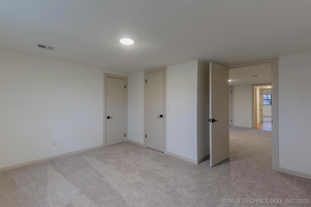 empty room featuring light colored carpet, baseboards, and visible vents