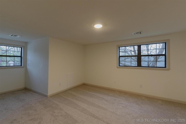 spare room featuring visible vents, light colored carpet, and baseboards