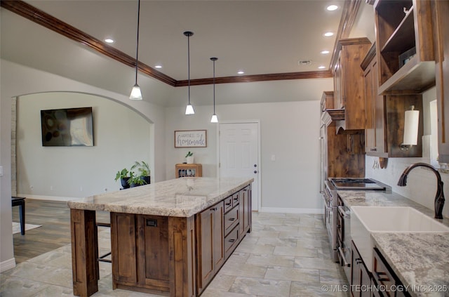 kitchen featuring baseboards, ornamental molding, a breakfast bar, and decorative light fixtures
