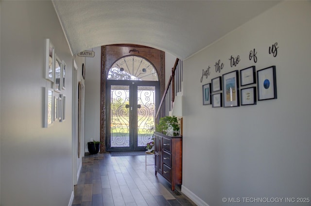entrance foyer featuring arched walkways, dark wood-style flooring, french doors, and baseboards
